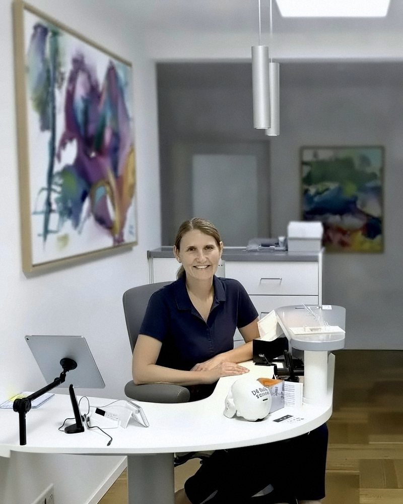Gaby Kukla am Empfang der Praxis Kukla, umgeben von Gemälden