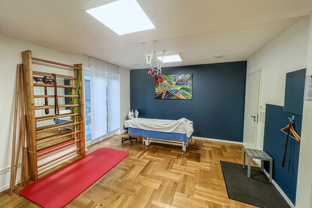 Therapieraum der Praxis Kukla mit Sprossenwand, Liege und Gemälde
