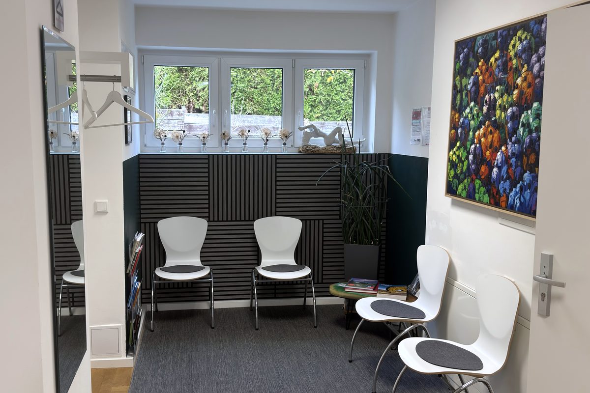 Wartebereich der Praxis Kukla mit weißen Stühlen, Fenster und buntem Gemälde